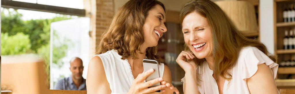 Mujeres observan tendencias en línea desde un teléfono móvil.