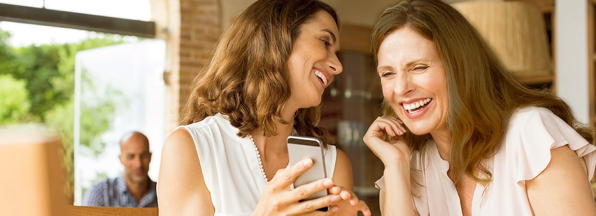 Mujeres observan tendencias en línea desde un teléfono móvil.